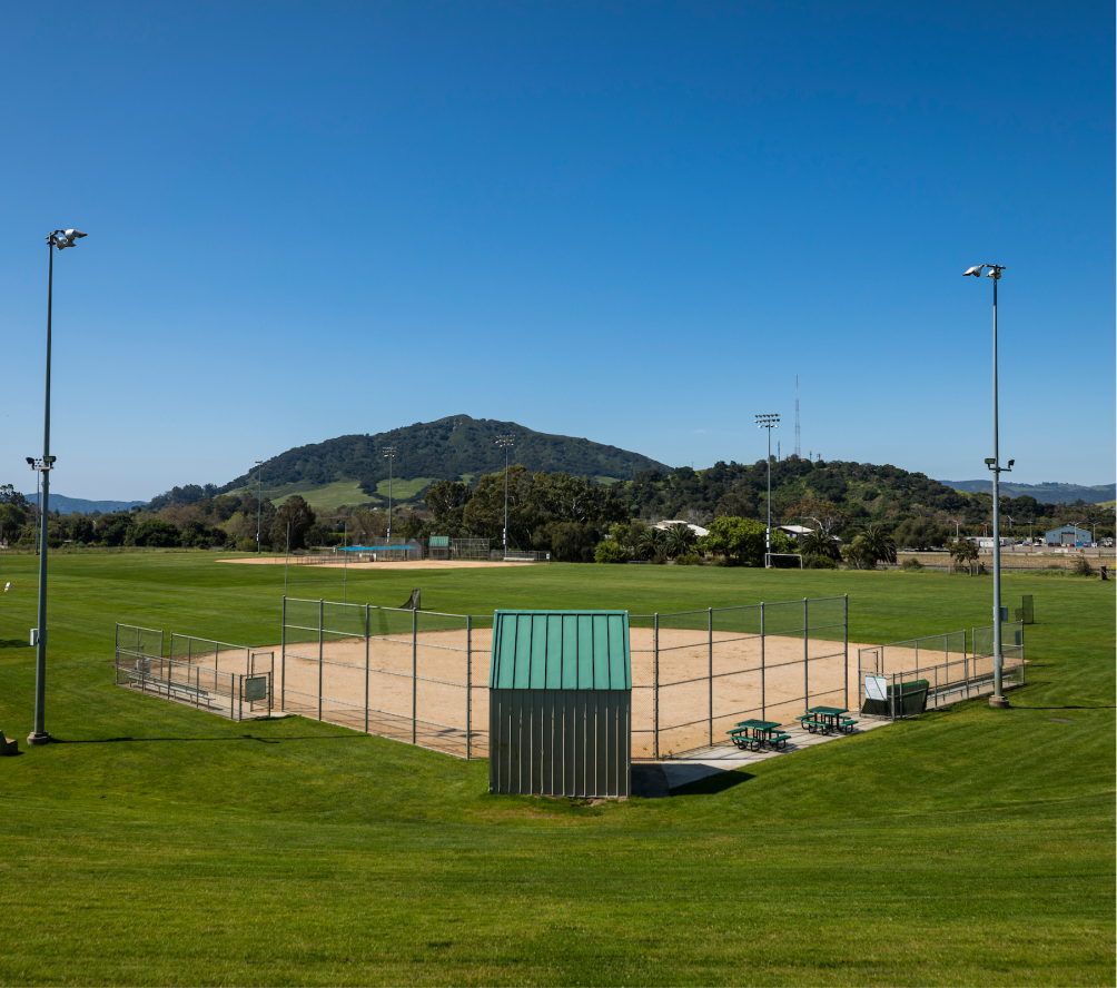 A view of the Cal Poly baseball and softball field surrounded by green grass with hills in the background.