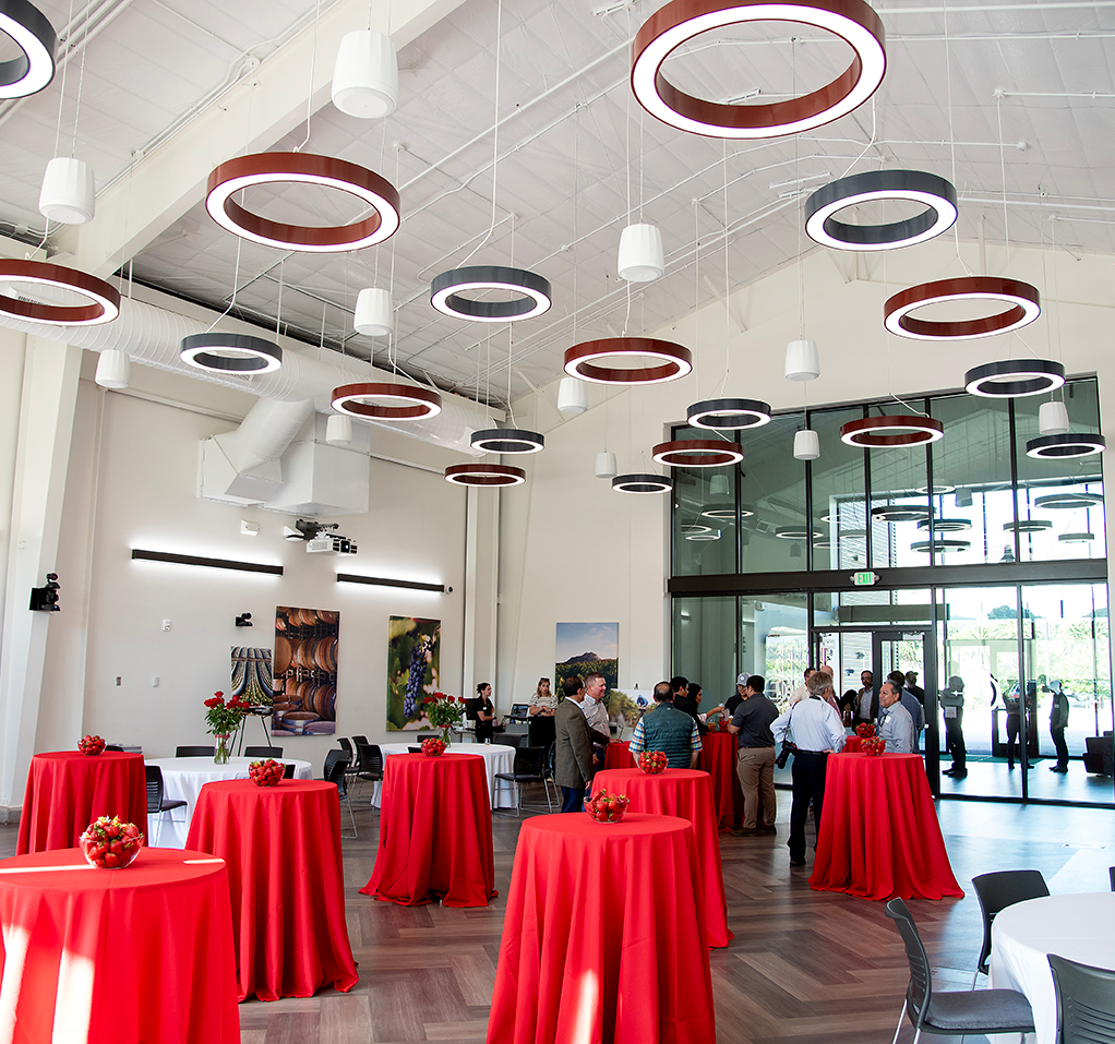 Interior view of Cal Poly event venue with red tablecloths, modern lighting, and guests mingling