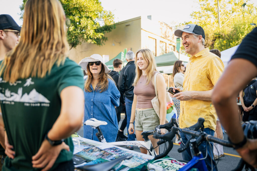 Cal Poly students and families interacting at an outdoor booth during a farmers market event