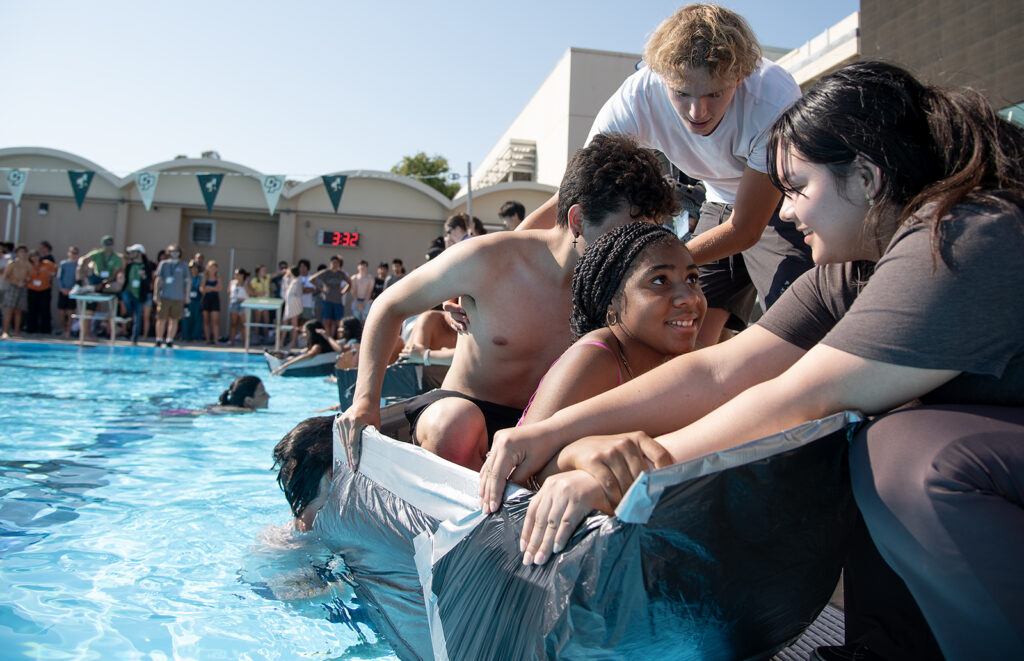 Students in a duct-taped cardboard boat participating in a pool race at Cal Poly