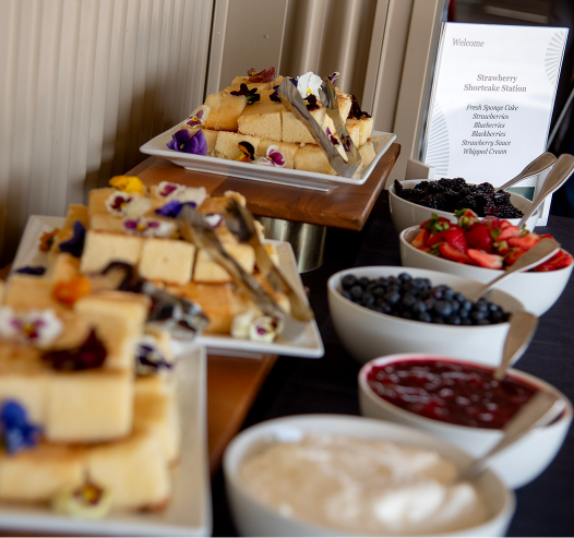 Plates of shortcake and bowls of fresh berries and cream at Cal Poly strawberry shortcake station