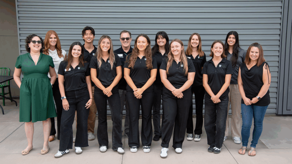 Group of smiling Cal Poly student ambassadors and staff posing in front of a building