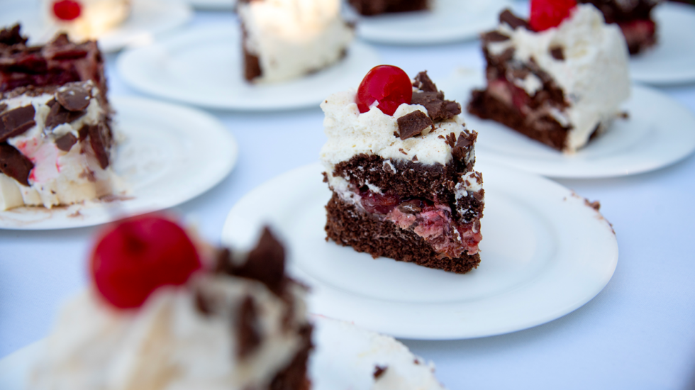 Close-up of cherry chocolate cake slices on white plates at an event.